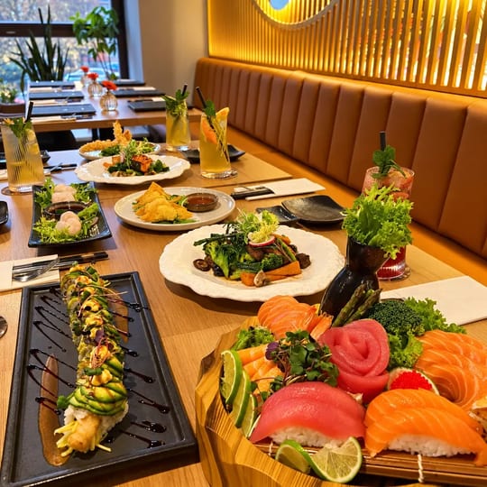 Dragon roll, sashimi a saláty na dřevěném stole u kožené lavice