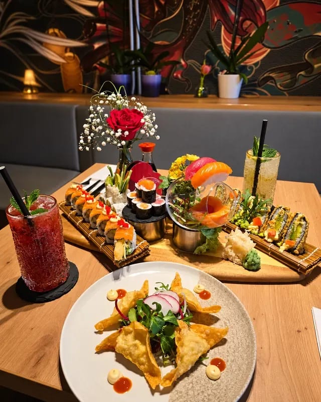 Smažené wontony, rolky sushi a koktejly na stole